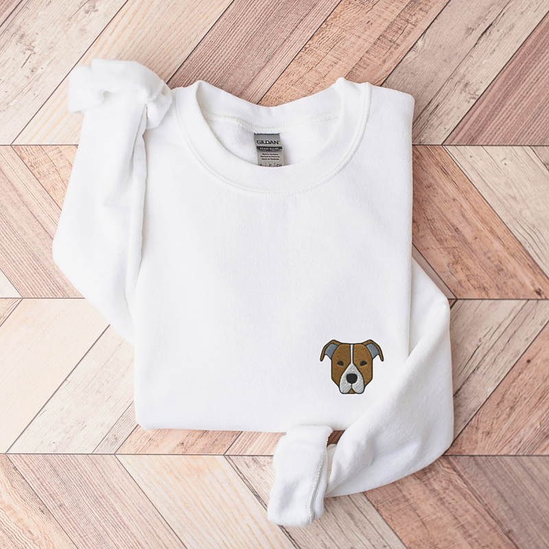 Minimalistično vezenje portreta ljubljenčka na beli majici z dolgimi rokavi.