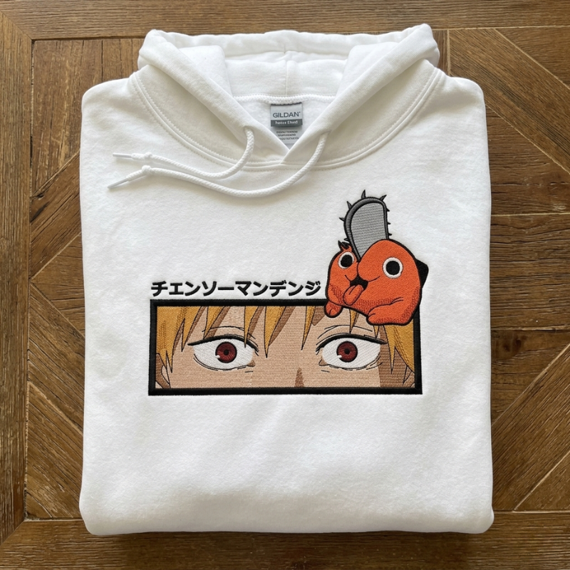 Personaliziran beli pulover s kapuco z natančnim vezenim portretom anime lika Denji s Pochito na prsih in japonskim napisom, izdelanim po fotografiji.