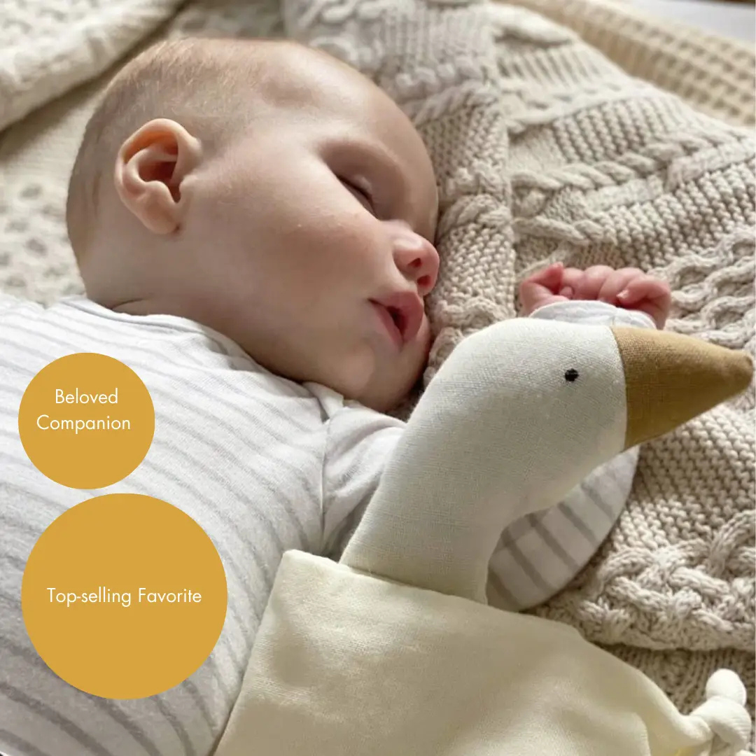 Zaspan novorojenček, ki leži na mehki pleteni odejici z ninico gosko. 